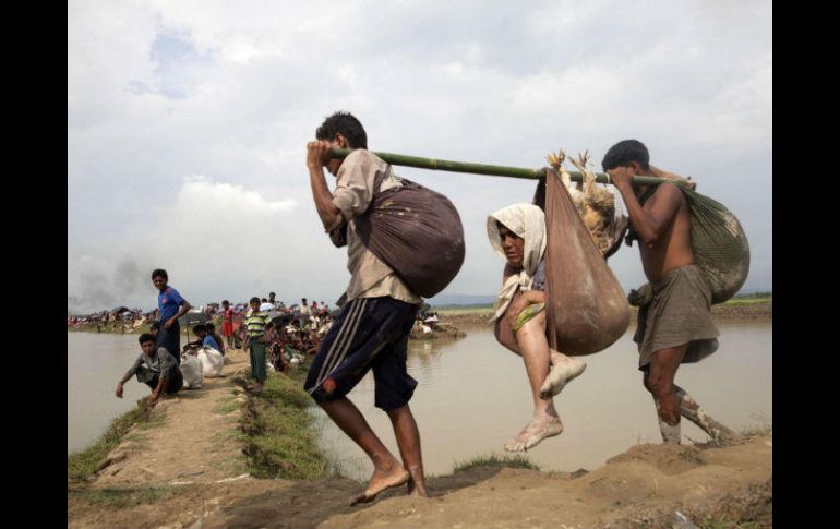 Dos hombres musulmanes de la minoría rohinyá llevan a una mujer mayor en Telnaf, al entrar en Bangladesh. EFE / STR