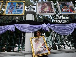 Una mujer sostiene un enorme cuadro del fallecido rey mientras espera a que comiencen las exequias. AFP/A. Wallace