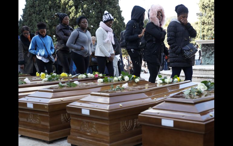 Mujeres pasan junto a ataúdes en el panteón de Salerno, Italia, en el funeral de 26 nigerianas que fallecieron la semana pasada al intentar cruzar el Mediterráneo para llegar a Italia. AP/A. Tarantino