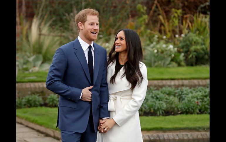 El príncipe Enrique de Inglaterra posa junto a su prometida, la actriz estadounidense Meghan Markle, tras anunciar su compromiso en el Jardín Sunken del Palacio Kensington, en Londres. . AP/M. Dunham