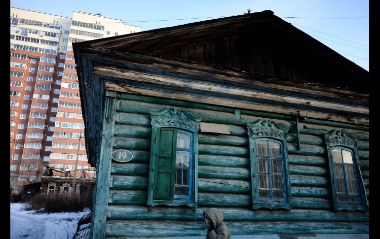 Una mujer pasa junto a una casa de madera en Blagoveshchensk, Rusia. Las temperaturas en la región de Amur bajaron hasta menos 12 grados centígrados. AFP/K. Kudryavtsev
