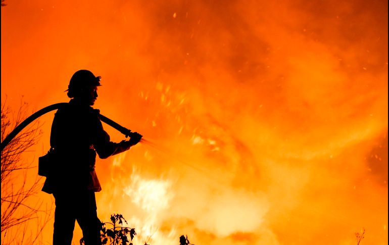 Un bombero combate un incendio forestal cerca de vivendas en la ciudad estadounidense de Santa Paula, en el estado de California. AFP/R. Chiu