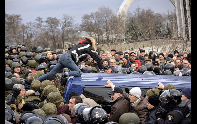 Una mujer se trepa al vehículo policial que traslada al ex presidente de Georgia, Mikheil Saakashvili, en enfrentamientos para tratar de liberarlo en Kiev, Ucrania. El opositor al poder ucraniano fue liberado poco después de su arresto. AFP/S. Chuzavkov