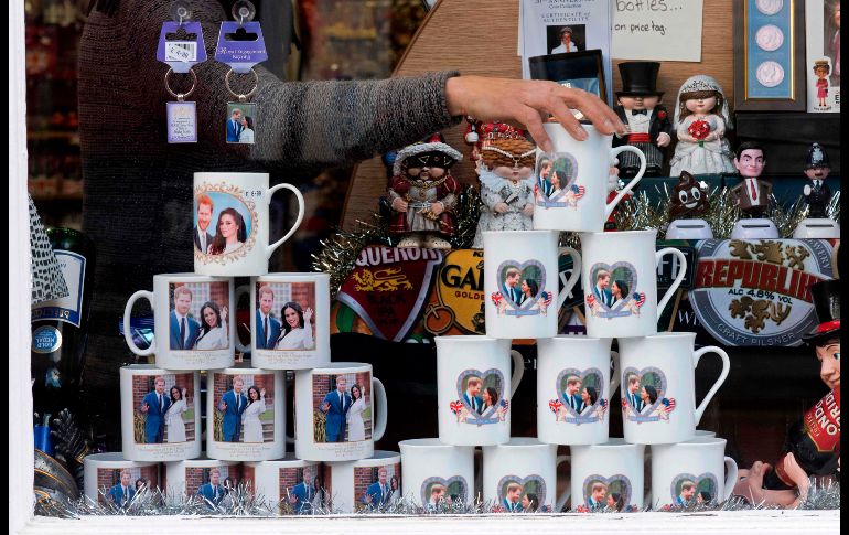 Un empleado acomoda en el exhibidor artículos conmemorativos del compromiso entre el Príncipe Harry y la actriz Meghan Markle en una tienda de Windor, en Londres. AFP / J. Tallis