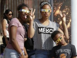 Jóvenes posan con lentes protectores para ver el eclipse solar en el Centro de Ciencias de California. EFE / M. Nelson