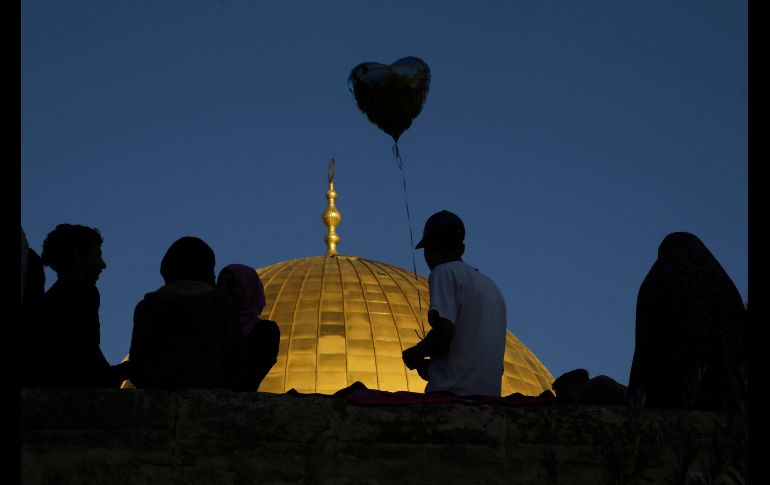 Un palestino sostiene un globo frente a la Cúpula de la Roca en Jerusalén, durante el rezo matutino de los musulmanes. AP/M.  Illean