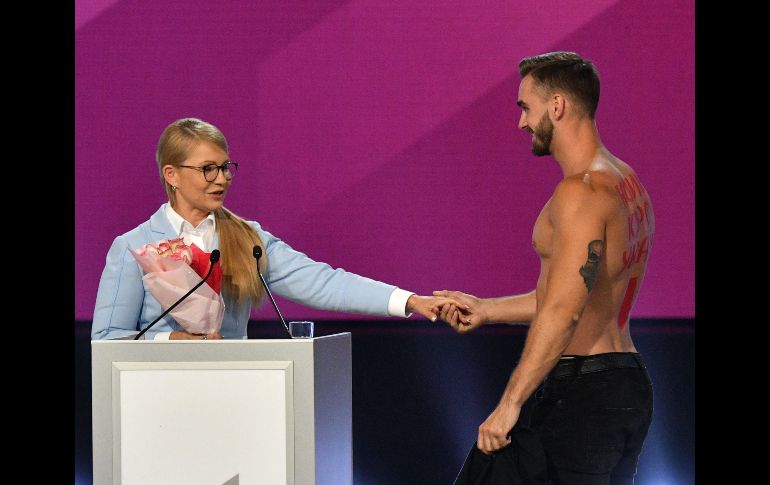 Un hombre sin camisa le ofrece flores a la ex primera ministra ucraniana, Yulia Tymoshenko, mientras da un discurso en un foro político en Kiev. Tymoshenko es una de las aspirantes para la contienda presidencial de 2019. AFP/F. Savilov