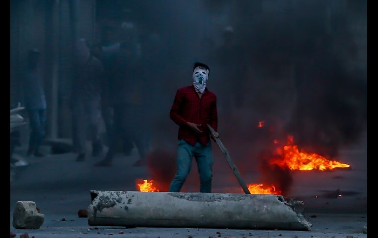 Un cachemir se manifiesta en Srinagar, India, mientras policías arrojan gas lacrimógeno. Separatistas cachemires llamaron a una huelga en protesta por las muertes de civiles y un peridista. AP/D. Yasin