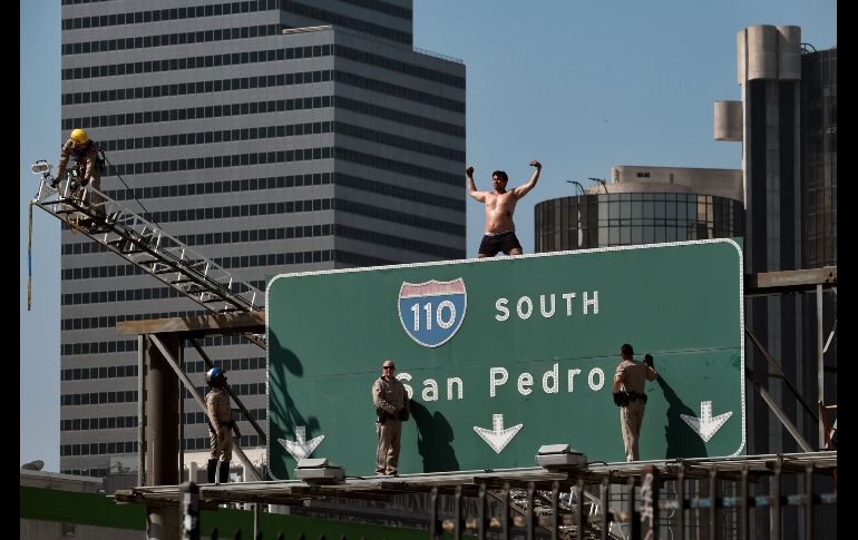 Policías intentan atrapar a un hombre que subió a una señal de tráfico en el centro de Los Ángeles, California. El sujeto trepó y colocó letreros, uno de ellos sobre el combate a la contaminación. AP/R. Vogel