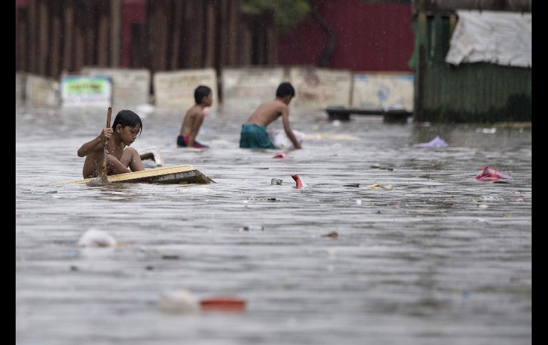 Un niño usa una balsa improvisada en una calle inundada en Marikina, Filipinas, tras el paso de la tormenta tropical 