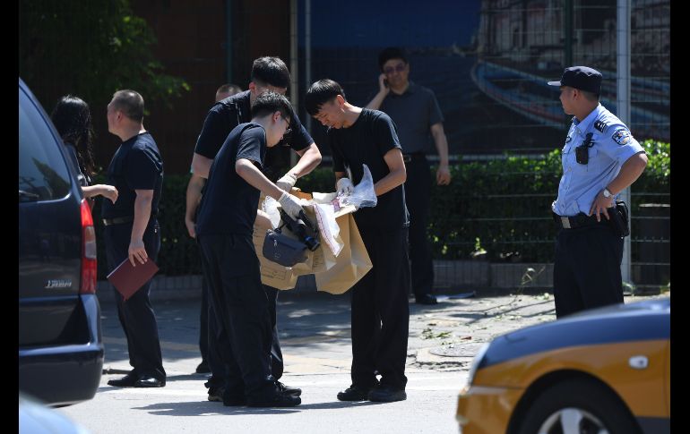 Oficiales de seguridad trabajan en el sitio donde un pequeño artefacto estalló hoy, en las afueras de la Embajada de Estados Unidos en Pekín, China, la cual causó heridas al autor del incidente. AFP/G. Baker