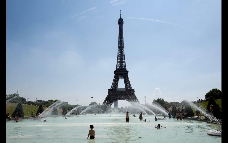 Personas se refrescan en la fuente del Trocadero, frente a la torre Eiffel de París. Una ola de calor afecta el norte de Europa. AFP/B. Guay