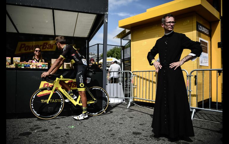 Un sacerdote se ve en Lourdes, Francia, mientras el ciclista Damien escoge un aperitivo previo al inicio de la decimonovena etapa del Tour de Francia. AFP/P. Lopez