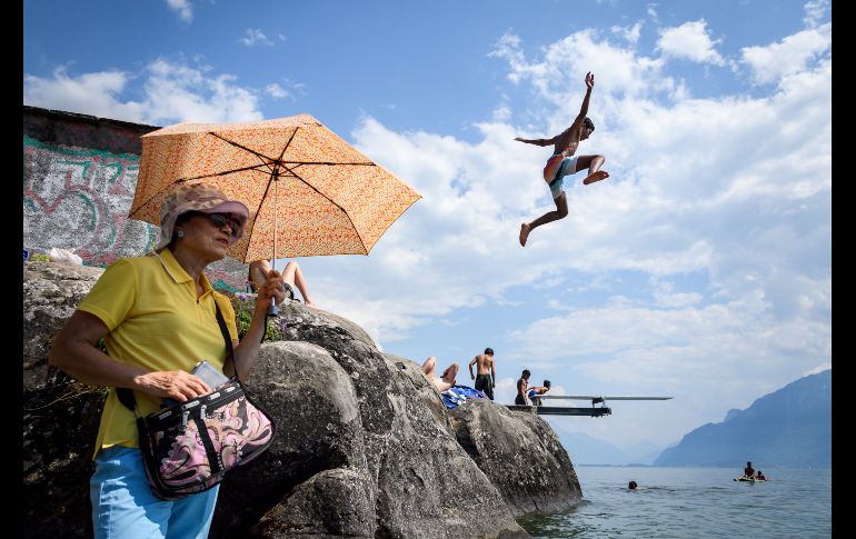 Un joven salta al lago Ginebra en Saint Saphorin, Suiza. Una ola de calor azota el norte de Europa. AFP/F. Coffrini