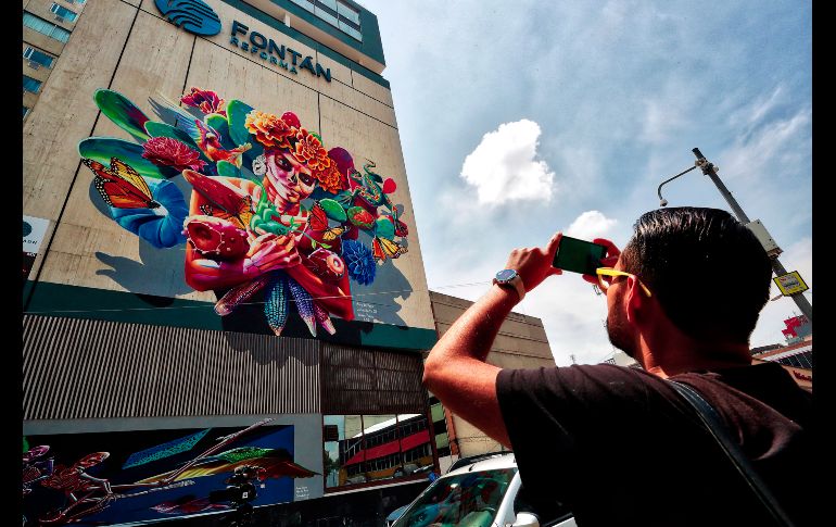 Un hombre toma una fotografía del mural titulado 