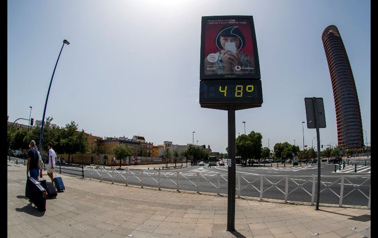 Turistas pasan junto a un termómetro de Sevilla que marca 48º centígrados debido a la ola de calor que en estos días dejará temperaturas extremas en la Península y Baleares. EFE/R. Caro