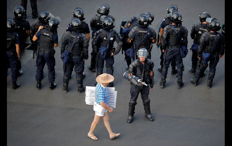 Un manifestante camina junto a policías antimotines afuera de oficinas gubernamentales en Bucarest, Rumania. Rumanos que viven en el extranjero protestan para exigir la renuncia del gobierno y un llamado a elecciones adelantadas. AP/V. Ghirda