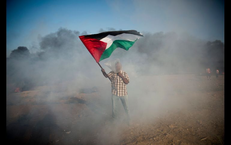 Un manifestante palestino se cubre del gas lacrimógeno con una bolsa, durante una protesta en la frontera de la Franja de Gaza con Israel. AP/K. Hamra