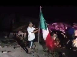 Un hombre sacó la Bandera de entre los escombros, buscó un mástil y la puso a ondear sobre una pila de tierra. ESPECIAL /