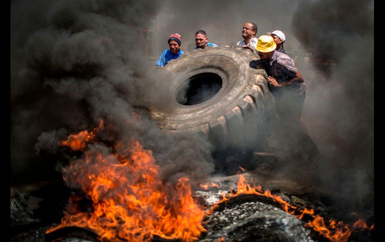 Integrantes de la comunidad de Ennerdale, en Sudáfrica, queman llantas durante una protesta  por la falta de acción policial en contra del abuso de drogas y en demanda de mejores condiciones de vivienda y servicios. AFP/G. Khan