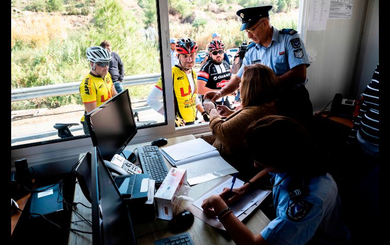 Oficiales chipriotas revisan documentos de ciclistas que pasan por un cruce recién abierto en Lefka. Por primera vez en ocho años, las autoridades de la dividida isla de Chipre abrieron dos nuevos puntos de paso entre el norte y el sur, coincidiendo con los intentos de la ONU de relanzar las negociaciones de reunificación. AFP/I. Hatzistavrou