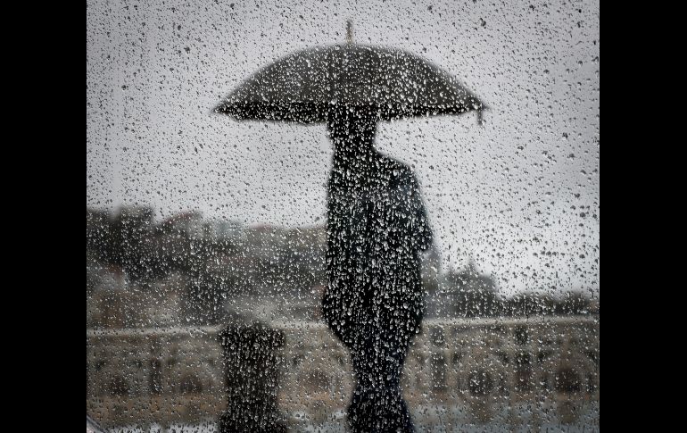 Un hombre camina bajo la lluvia en la ciudad española de San Sebastián. EFE/J. Etxezarreta