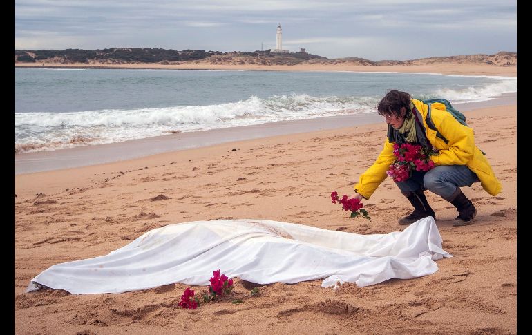 Una mujer coloca flores alrededor de uno de los cadáveres aparecidos de los inmigrantes que naufragaron en una patera en la costa de Caños de Meca, España. El número de víctimas de este siniestro se elevó a 18. EFE/R. Ríos