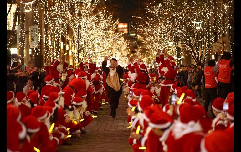 Personas en atuendos de Santa Claus participan en un desfile bajo luces festivas en el distrito financiero de Marunouchi, en Tokio. AFP/K. Nogi