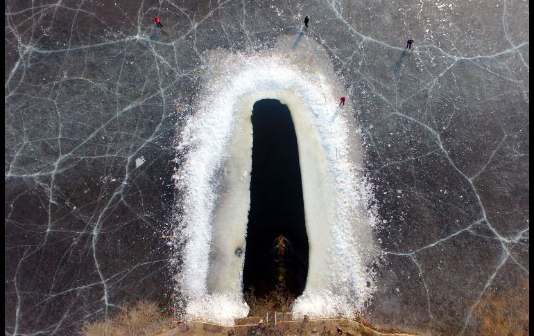 Un hombre nada en un área donde se cortó hielo en un lago congelado de Shenyang, China. AFP