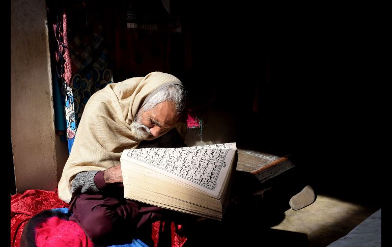 Un vendedor de prendas de mujer lee el Corán en Lahore, Pakistán, mientras espera clientes. AFP/A. Ali