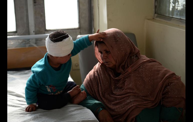 Una afgana se sienta junto a un niño herido que recibe atención en un hospital, luego de un ataque con bomba en Kabul. AFP/S. Rahmani