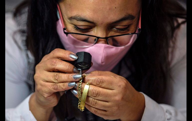 Una trabajadora del Nacional Monte de Piedad hace una valuación de una pieza de joyería de oro. AFP/P. Pardo