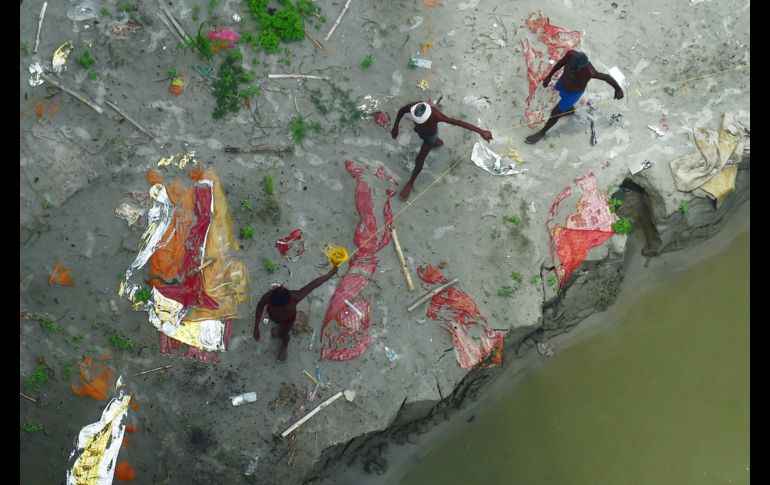 Pescadores locales se ven caminar junto a los cadáveres que salieron de sus tumbas. AFP/S. Kanojia