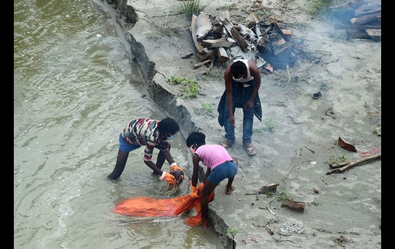 Trabajadores del gobierno al mover un cuerpo enterrado a las orillas del Ganges para proceder a cremarlo.  AFP/S. Kanojia