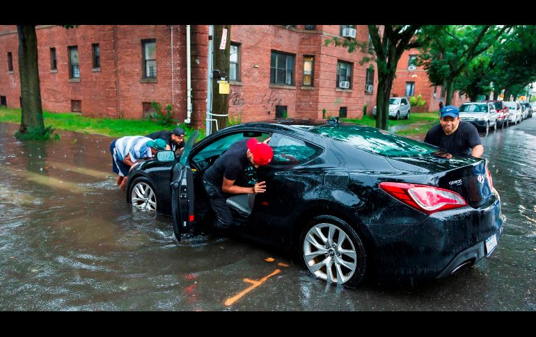 Personas empujan a un caro que quedó en una calle que se inundó en la ciudad de Nueva York.EFE/J. Lane