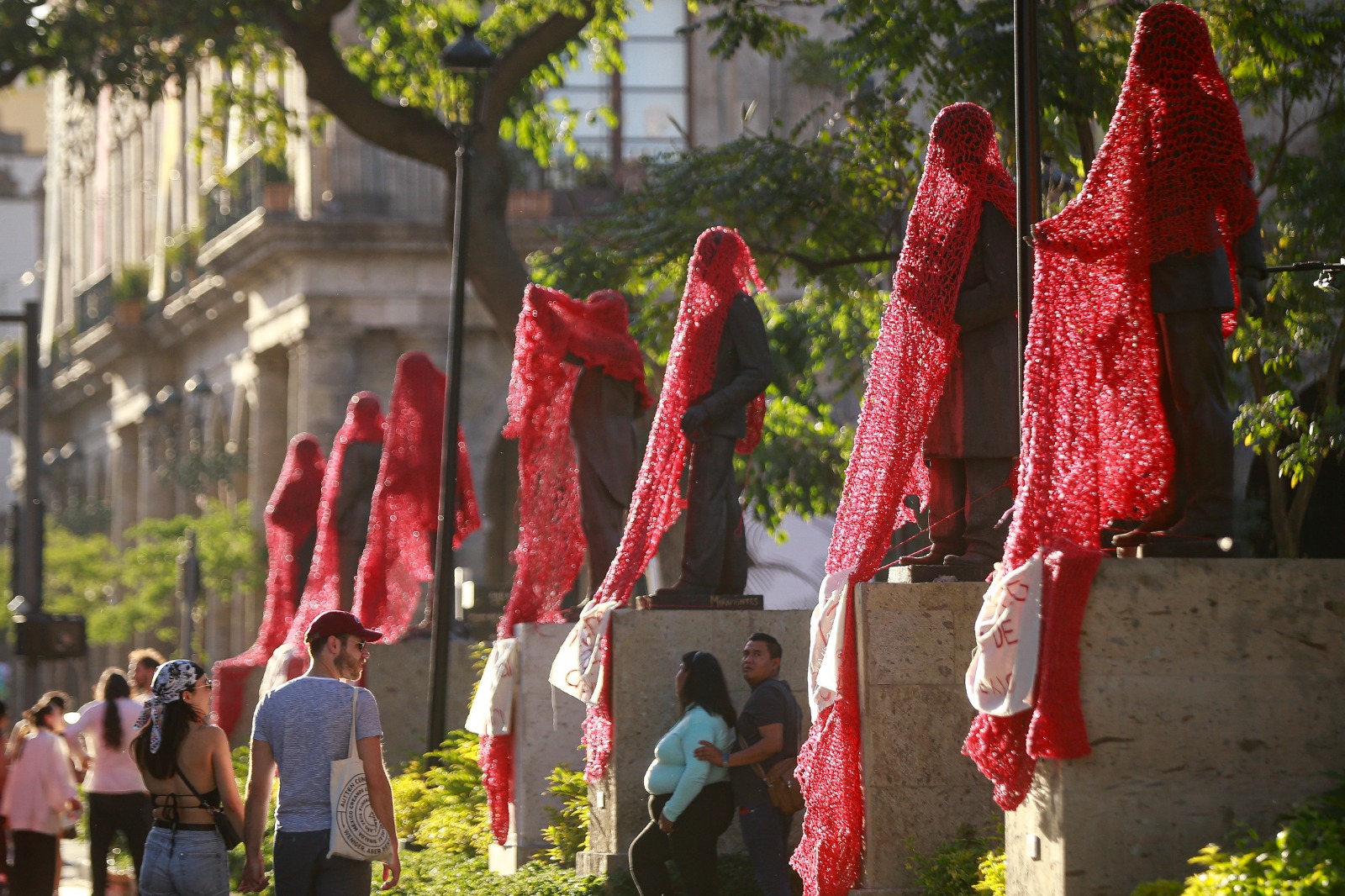 Mujeres de Colectiva Hilos cubrieron las estatuas de la rotonda de los hijos ilustres con redes de hilo rojo para reemplazar sus nombres por los de mujeres. EL INFORMADOR/ CARLOS ZEPEDA