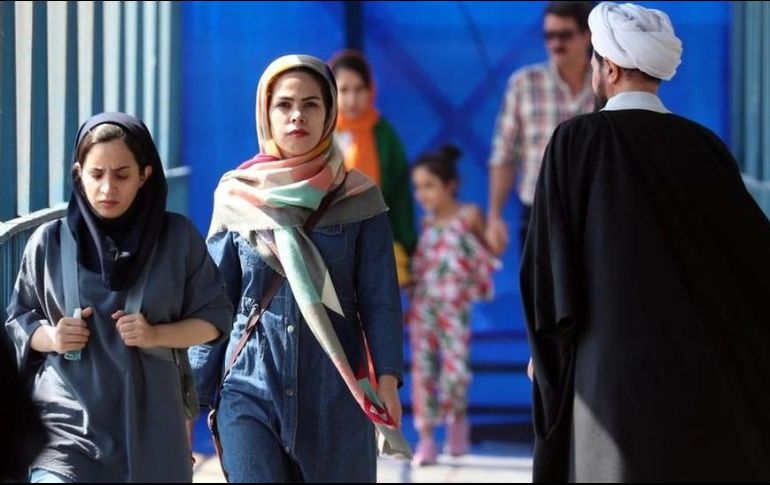 Mujeres iraníes caminan junto a un clérigo en una calle de Teherán en septiembre de 2022. EPA