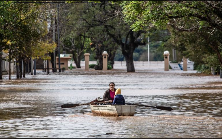 Una mujer acompañada de un niño conduce una embarcación por una calle inundada este lunes en Concordia (Argentina).  EFE/ Ignacio Jesús Rollano