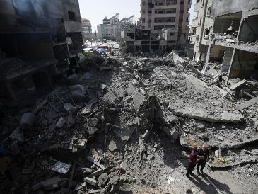 Palestinos revisan la destrucción causada por un bombardeo israelí en el campo de refugiados de Nuseirat. AP/Jehad Alshrafi/archivo