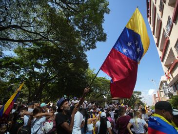 Un hombre agita una bandera de Venezuela en una concentración de venezolanos con motivo de las elecciones presidenciales en su país, este domingo en Cali, Colombia. EFE/ E. Guzmán